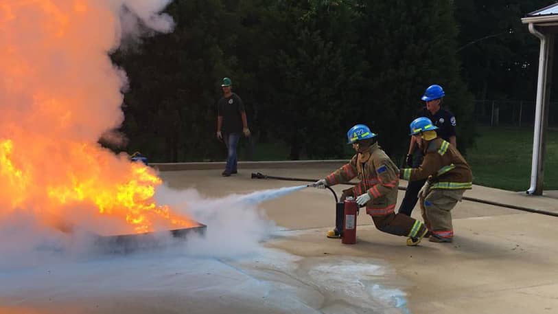 Three firefighters putting out a fire with a fire extinguisher